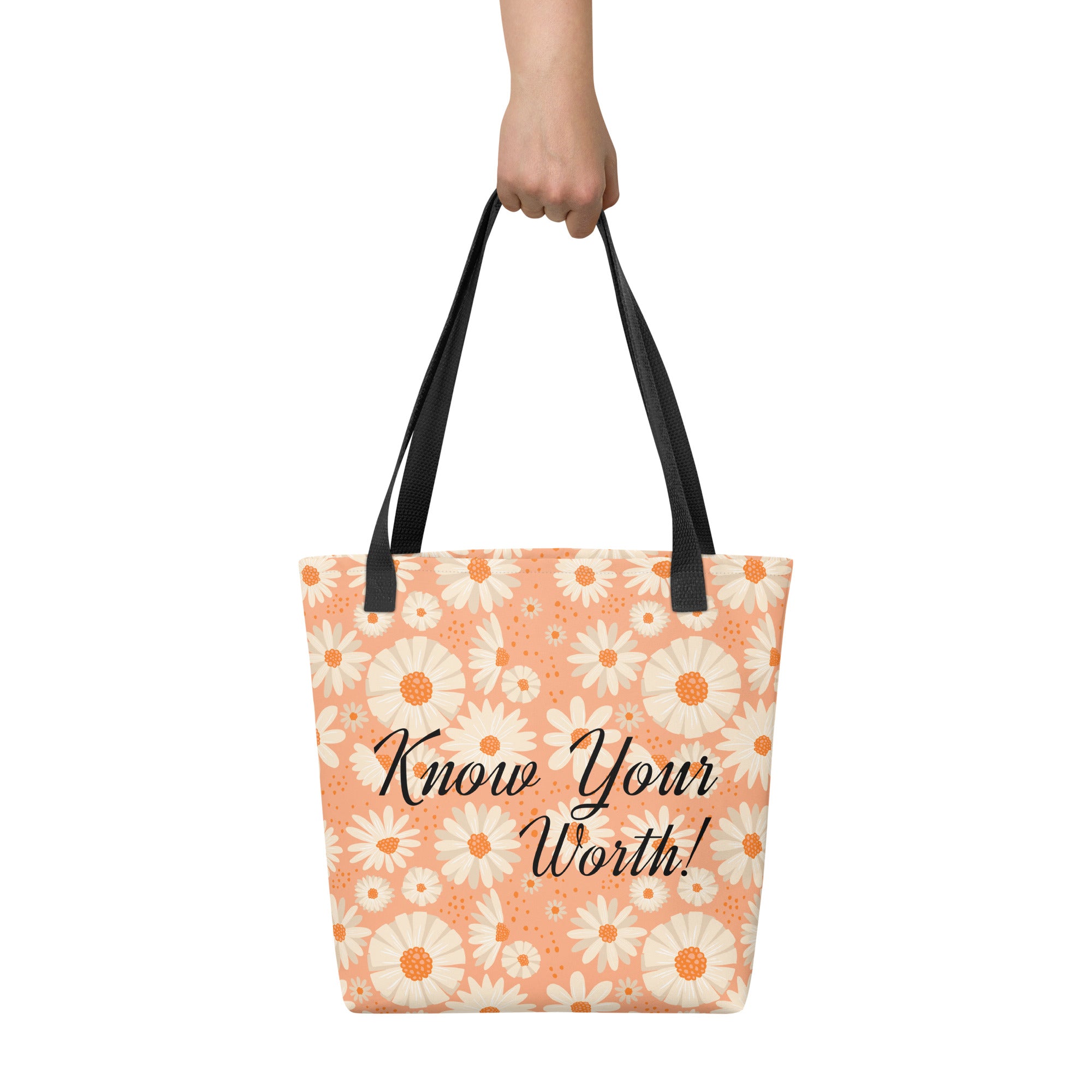 All-over white daisy print tote bag with a pastel pink background “Know Your Worth” text on the front and black denim shoulder straps