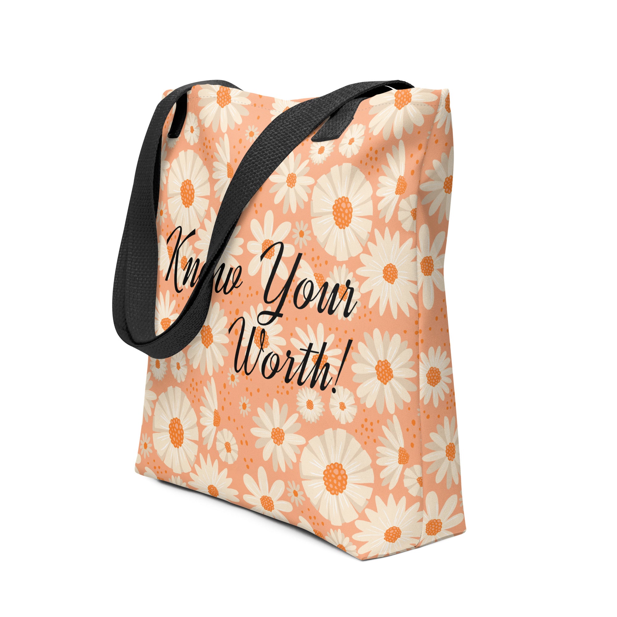 All-over white daisy print tote bag with a pastel pink background “Know Your Worth” text on the front and black denim shoulder straps